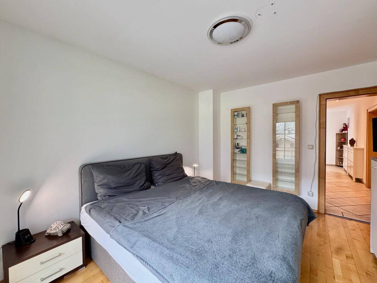 Helles Schlafzimmer mit Doppelbett, Nachttischen und Zugang zu einem weiteren Raum.