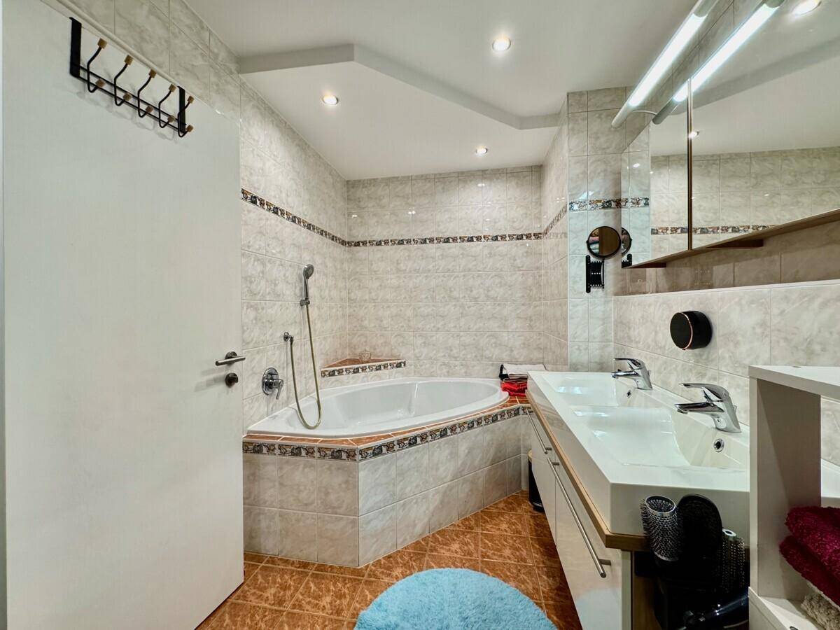 Geräumiges Badezimmer mit Eckbadewanne, Doppelwaschbecken und hellen Fliesen.