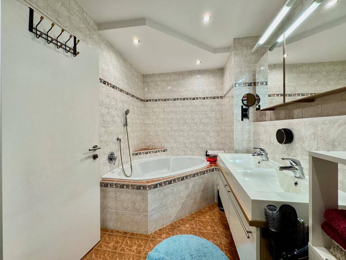 Geräumiges Badezimmer mit Eckbadewanne, Doppelwaschbecken und hellen Fliesen.