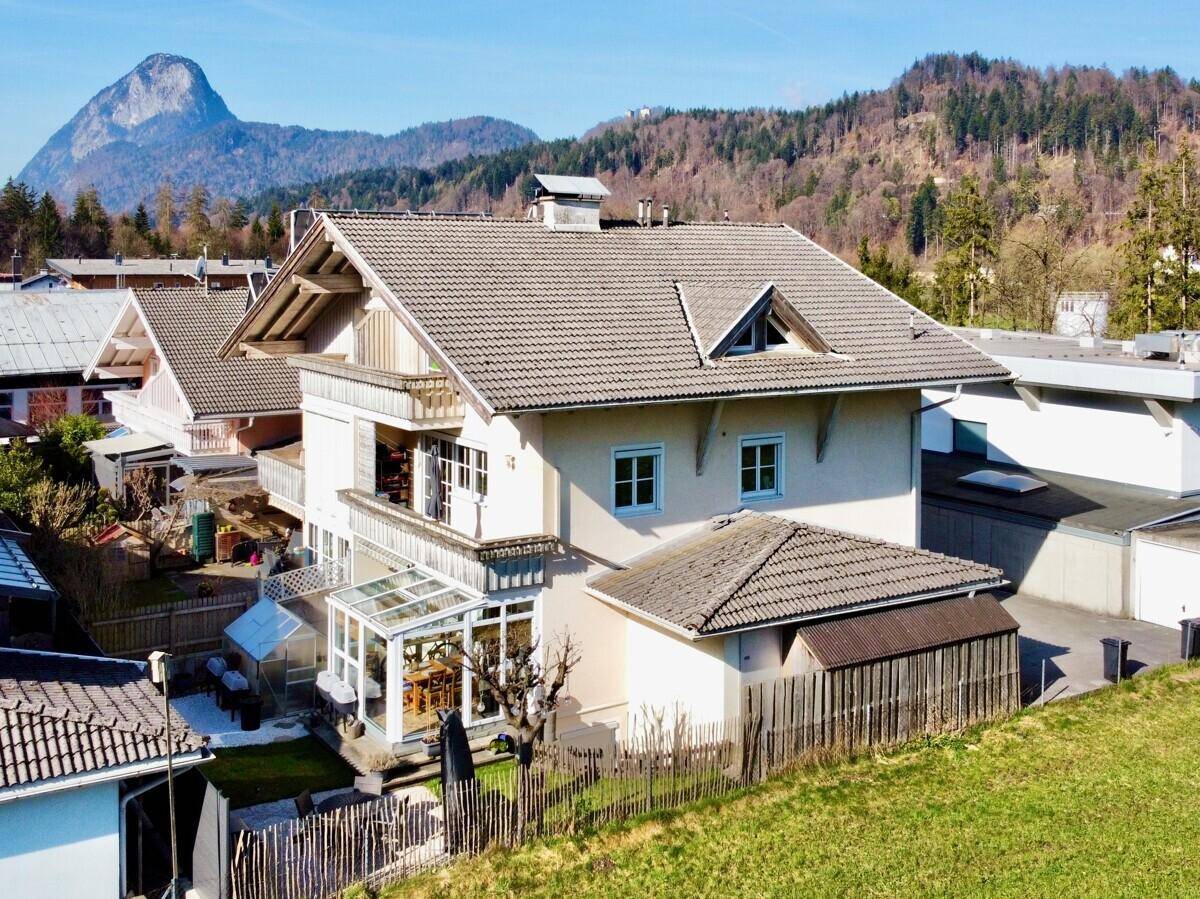 Rückansicht des Hauses mit Wintergarten, Gartenbereich und beeindruckendem Bergblick.