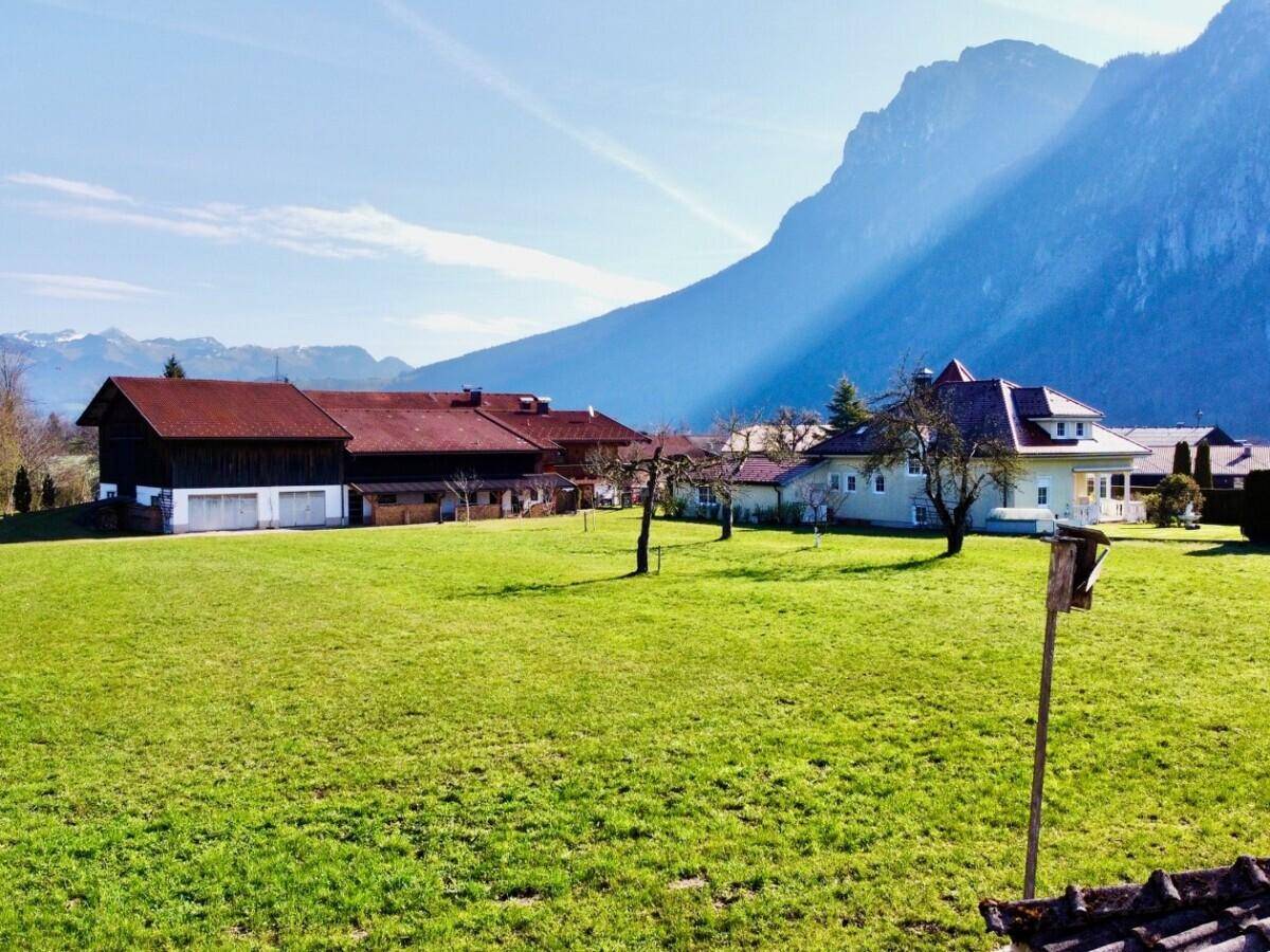 Weitläufige Grünfläche mit Blick auf die umliegende Berglandschaft und traditionelle Häuser.