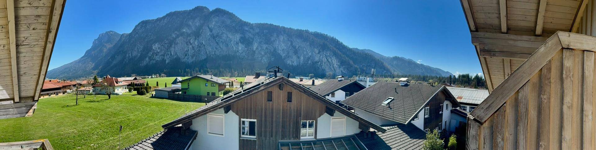 Panoramablick auf die umliegende Berglandschaft und Wohnhäuser.