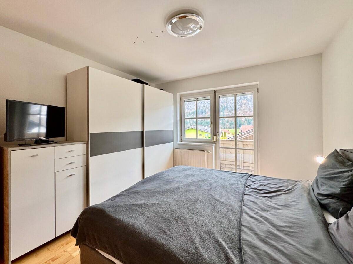 Helles Schlafzimmer mit Doppelbett, modernem Kleiderschrank und Fenster mit Bergblick.