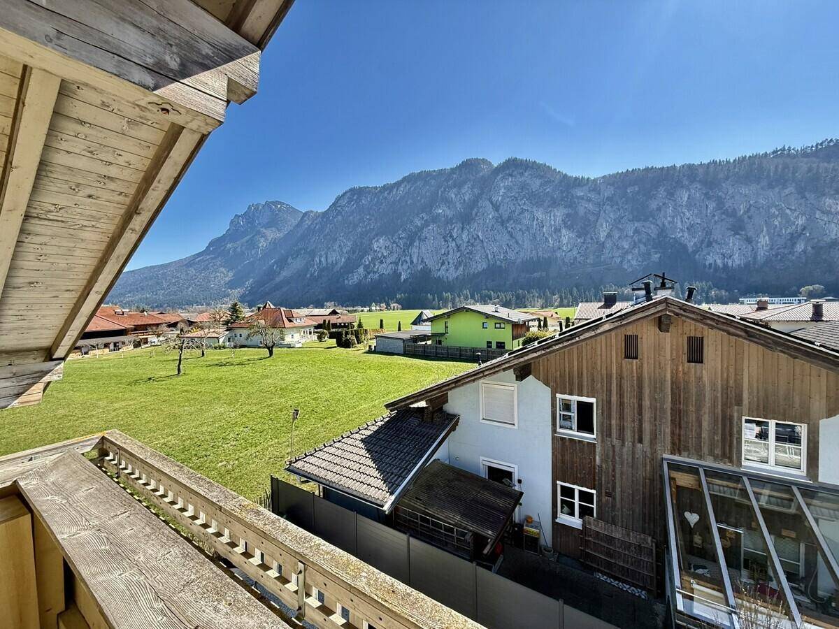 Weitläufiger Ausblick vom Balkon auf grüne Wiesen und die beeindruckende Bergwelt.