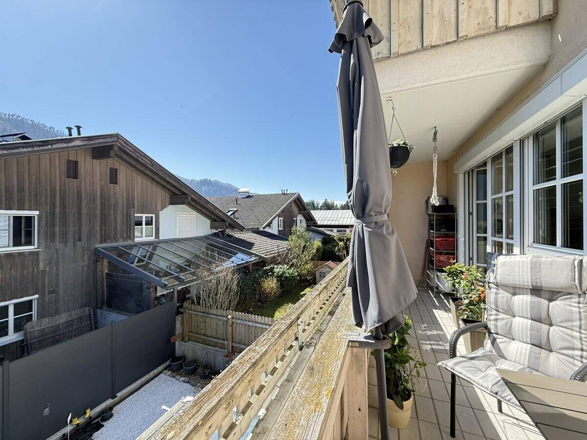 Geräumiger Balkon mit Sonnenschirm und Blick auf die umliegenden Gärten und Häuser.