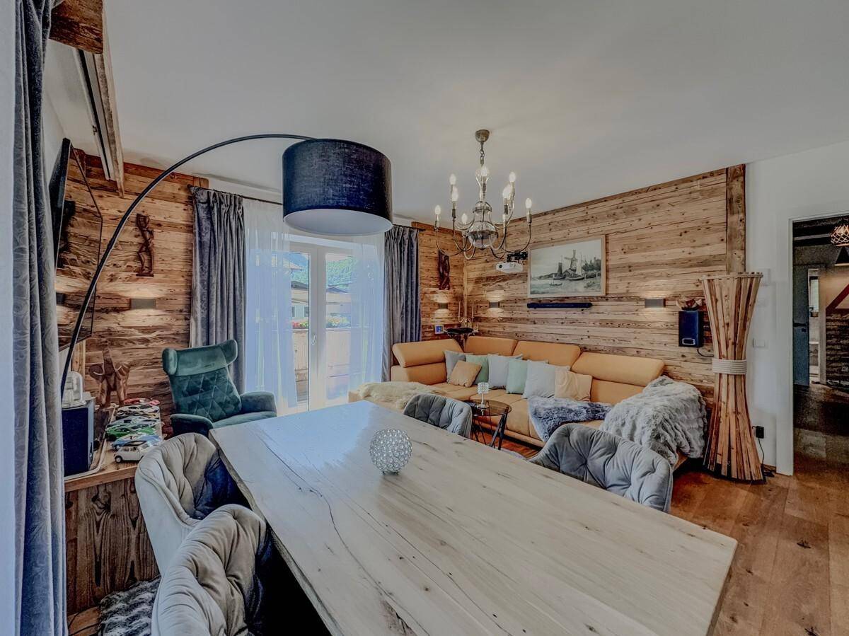Geräumiger Wohn-Essbereich mit großem Holztisch, bequemer Couch und stilvoller Beleuchtung.