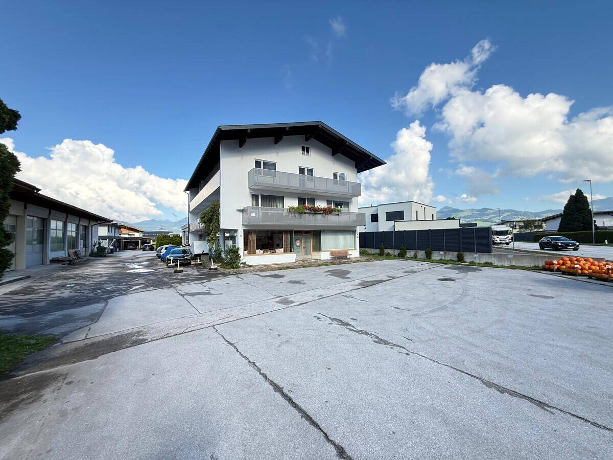 Gebäude mit Parkplatz und umliegender Landschaft unter einem klaren blauen Himmel.