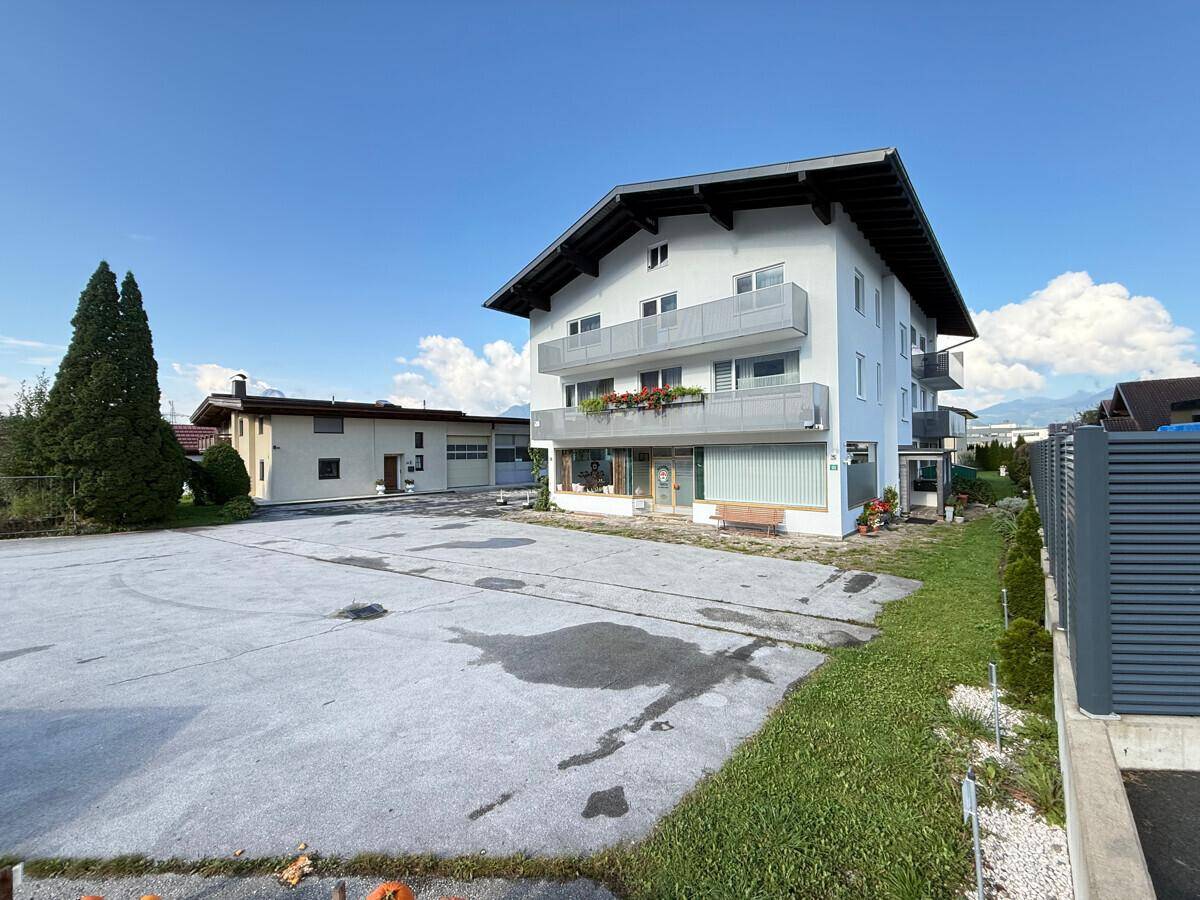 Seitenansicht des Gebäudes mit großem Parkplatz und angrenzender Grünfläche.