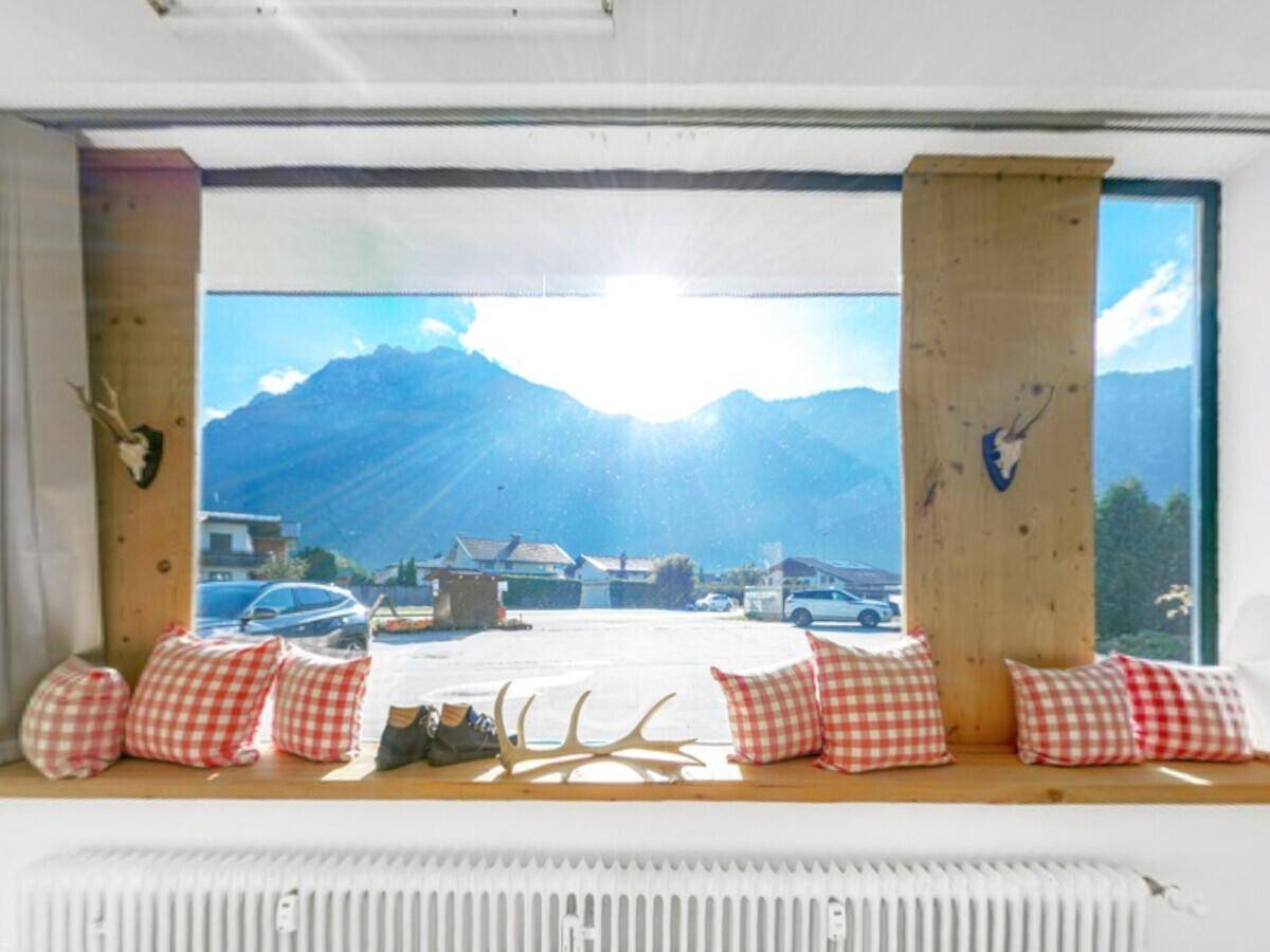 Fensterbereich mit Sitzgelegenheit, karierten Kissen und weitem Blick auf die Berge.