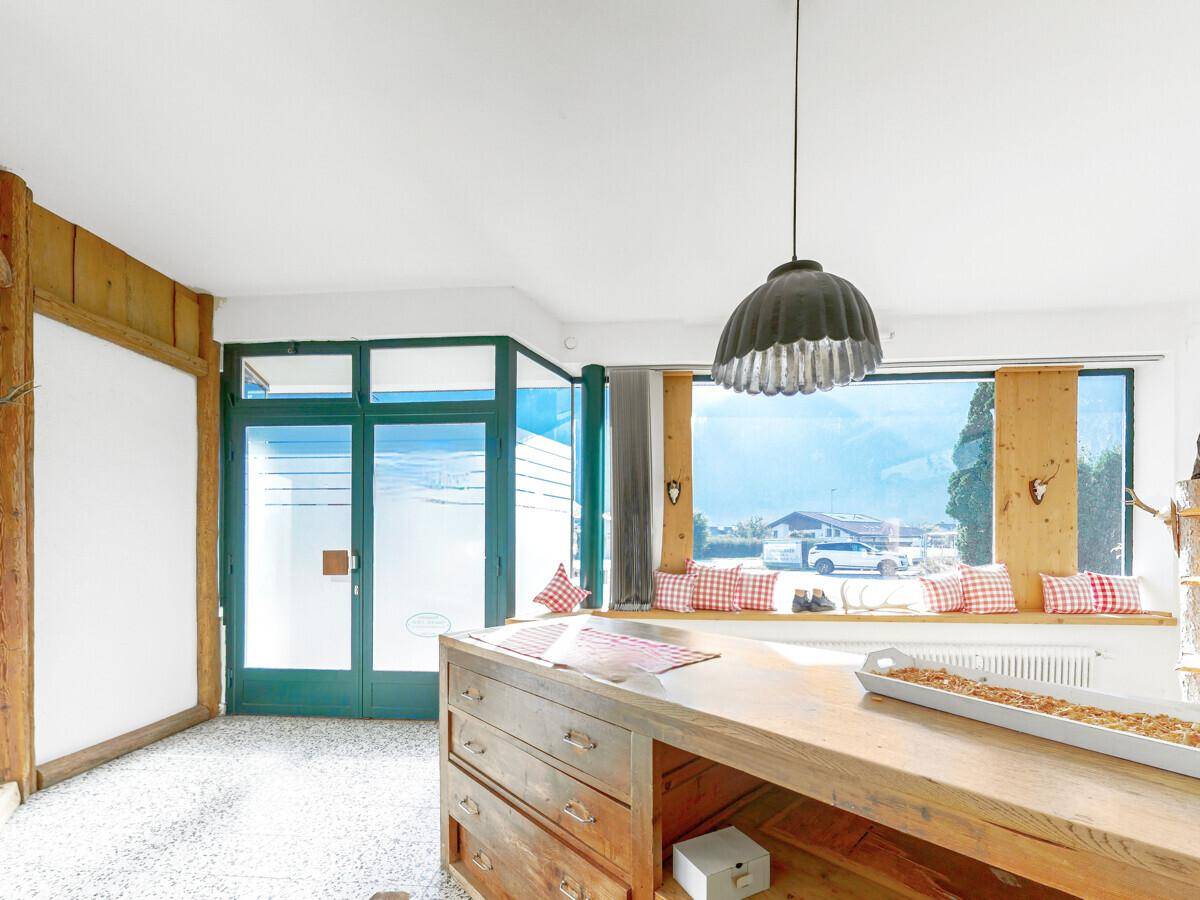 Innenraum mit Holztresen, großer Fensterfront und Blick auf die umliegende Berglandschaft.