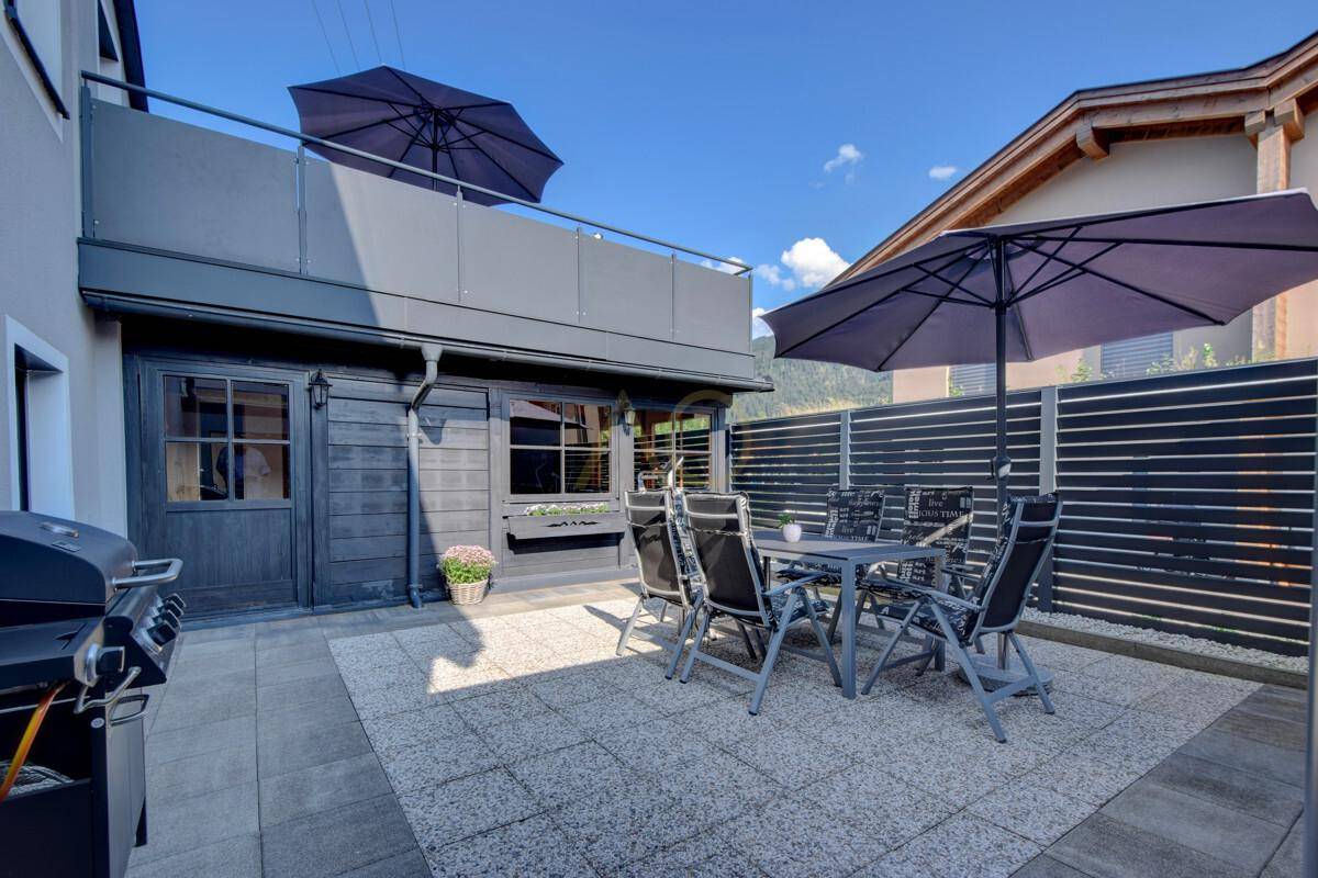 Gemütliche Terrasse mit Gartenmöbeln, Grillbereich und Sonnenschirmen.