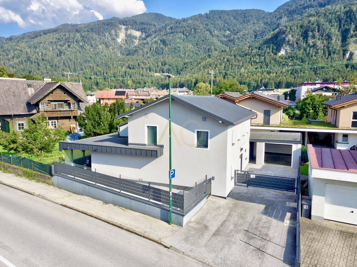 Neubau-Einfamilienhaus mit Garage, gepflasterter Zufahrt und Bergblick.
