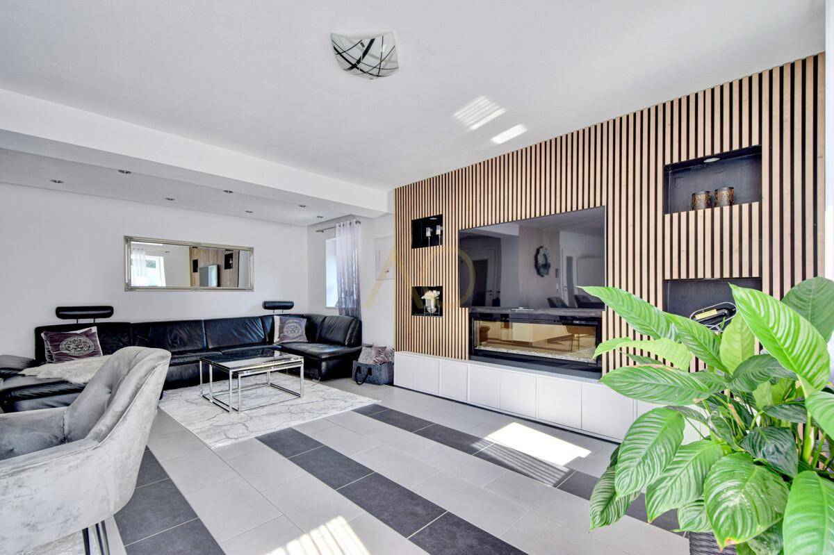 Helles Wohnzimmer mit moderner Einrichtung, Holzwand und integriertem Kamin.