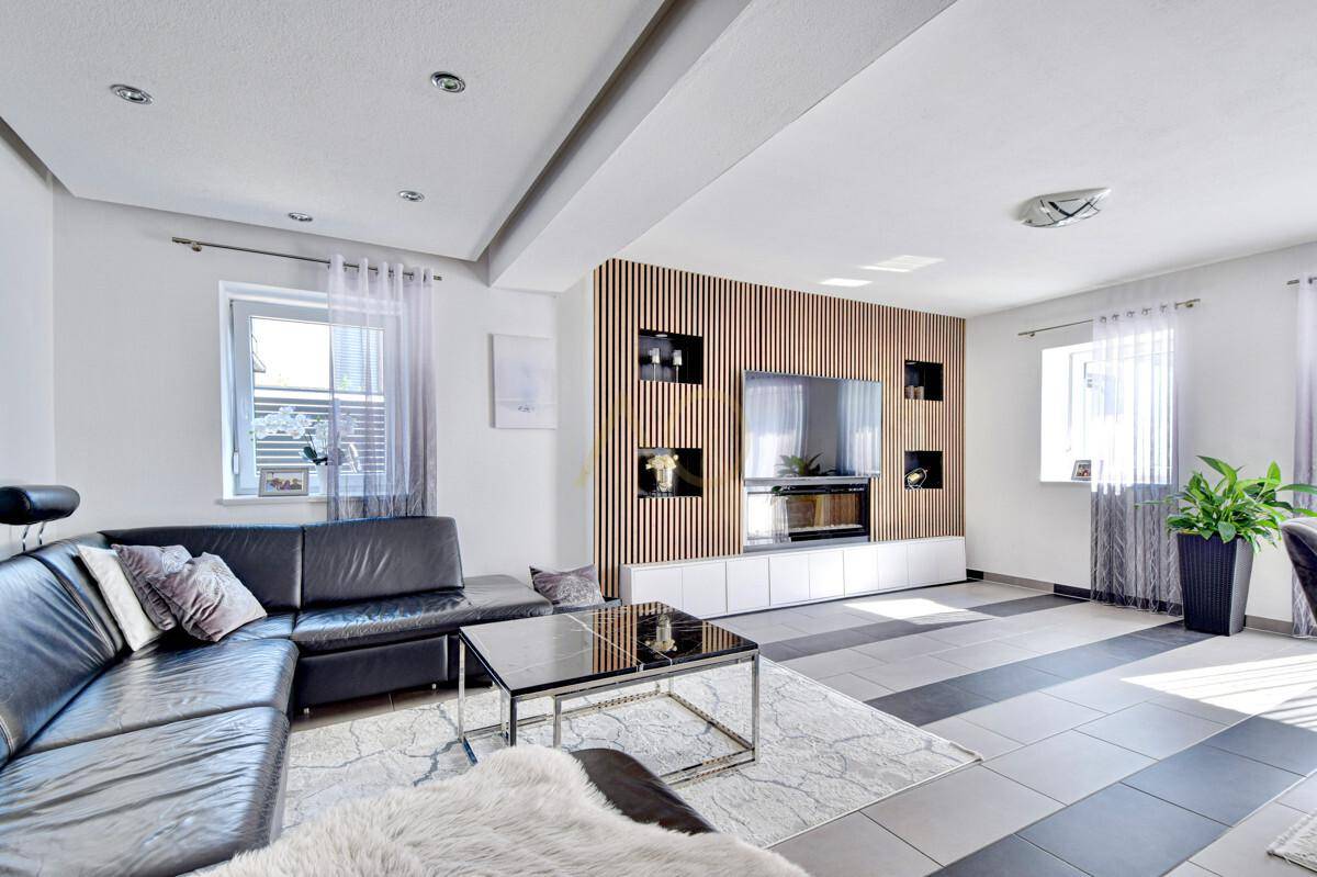 Geräumiges Wohnzimmer mit bequemer Ledercouch und dekorativer Holzwand.