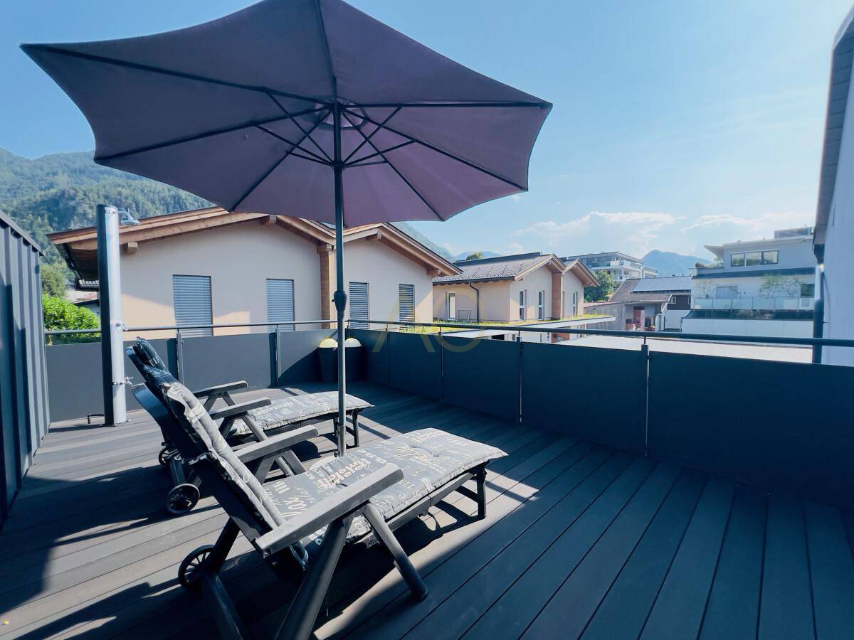 Großer Balkon mit Liegestühlen und weitem Blick auf die umliegende Berglandschaft.