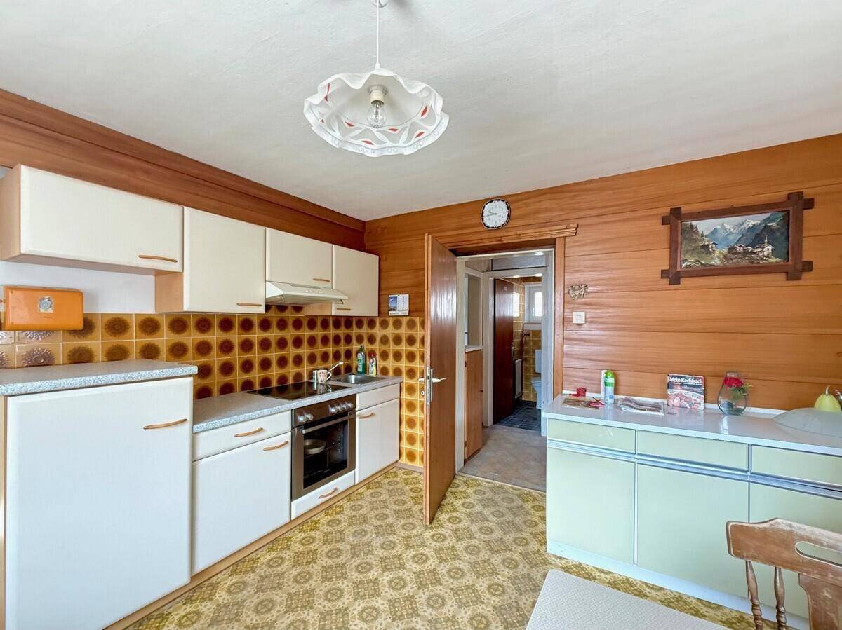 Küche im traditionellen Stil mit Holzvertäfelung, gemusterten Fliesen und älteren Einbaumöbeln.