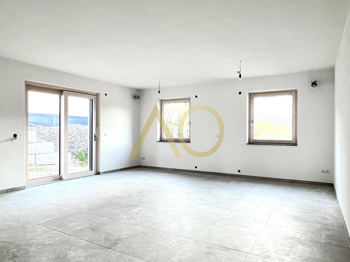 Helles Wohnzimmer mit großen Fliesen, weiß gestrichenen Wänden und Zugang zur Terrasse.