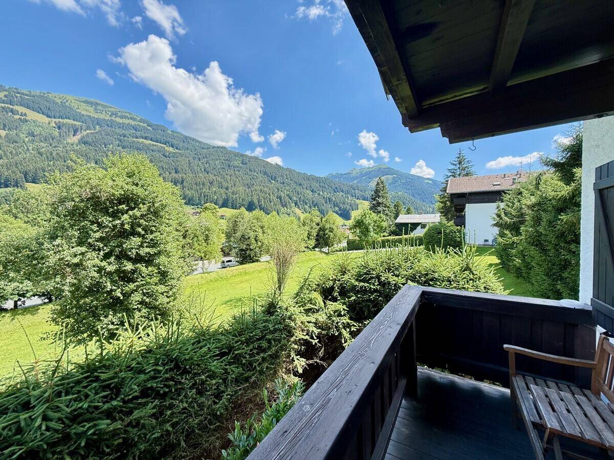 Kleiner Balkon mit Holzboden und Sitzbank, bietet einen weiten Blick auf die Berge.