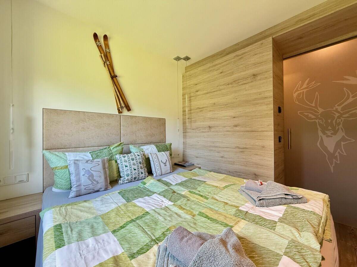 Schlafzimmer mit Doppelbett, Holzwandverkleidung und Hirschmotiv auf der Schiebetür.
