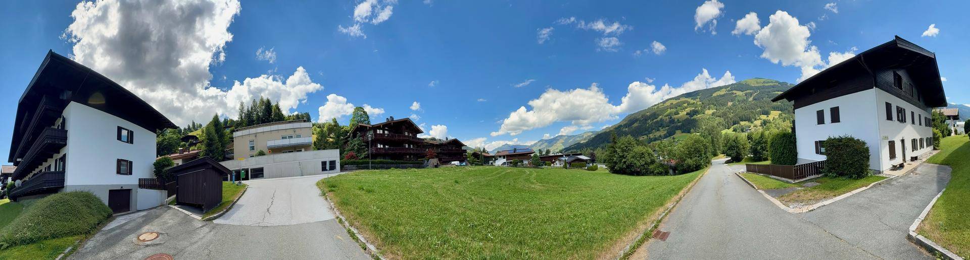 Panoramablick auf mehrere Gebäude im alpinen Stil mit grünen Wiesen und Bergen.