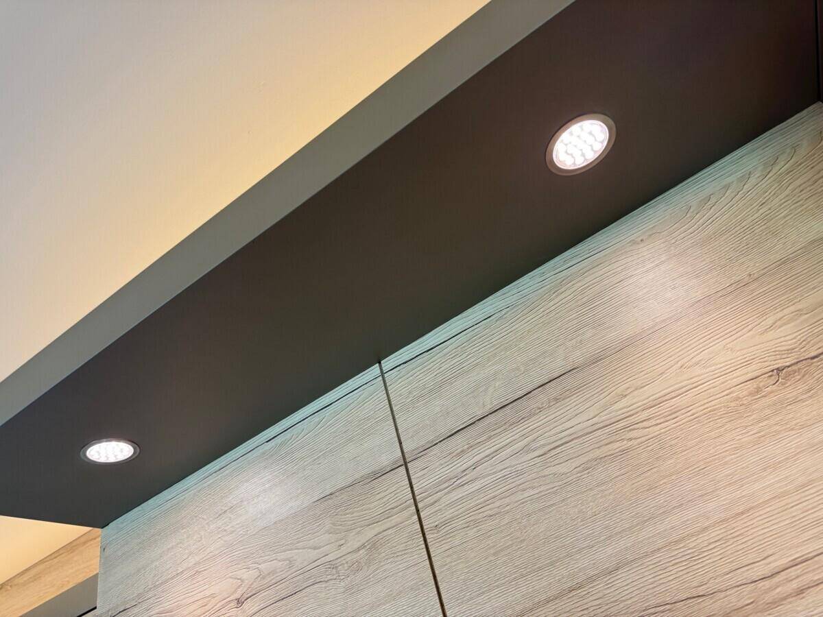 Deckenbeleuchtung mit Einbaustrahlern über den modernen Holzschränken.