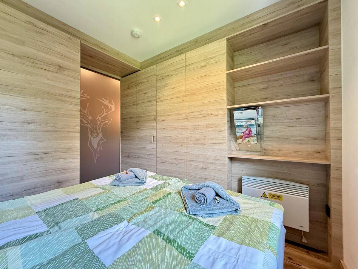 Schlafzimmer mit Doppelbett, integrierten Holzschränken, Regalen und Schiebetür mit Hirschmotiv.