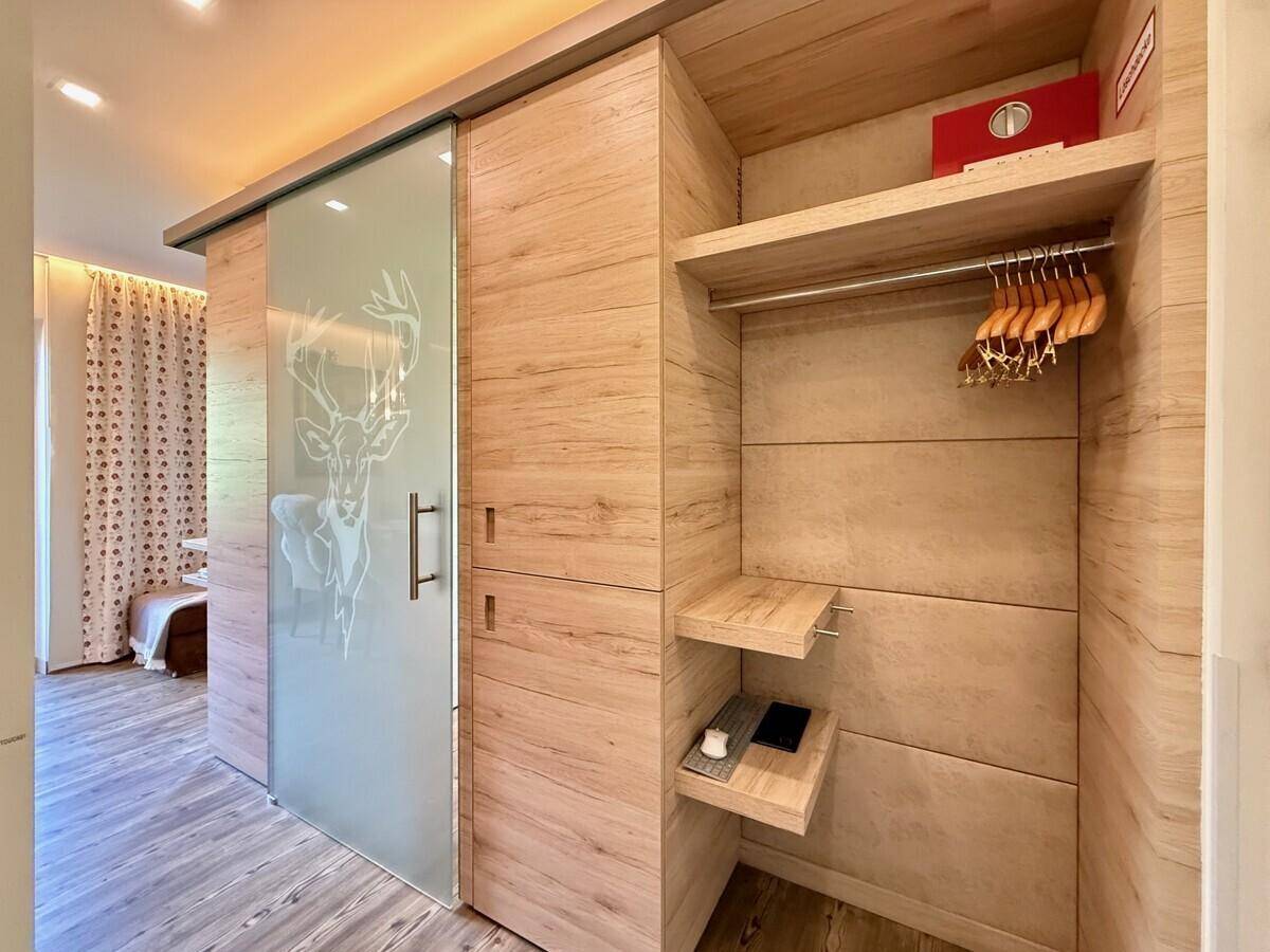Modernes Ankleidezimmer mit Holzverkleidung und Schiebetür, die zum Schlafzimmer führt.