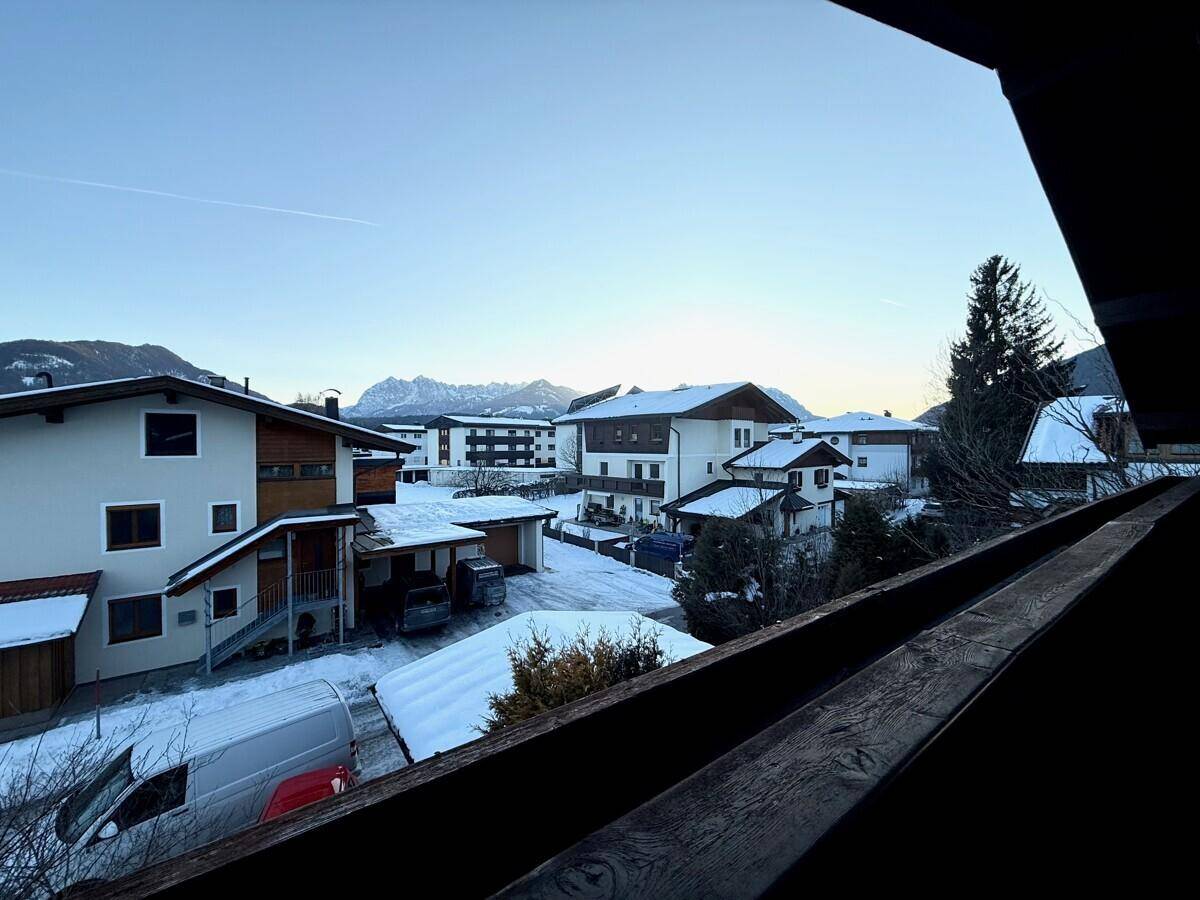 Panoramablick vom Balkon auf eine verschneite Wohngegend und die umliegenden Berge.