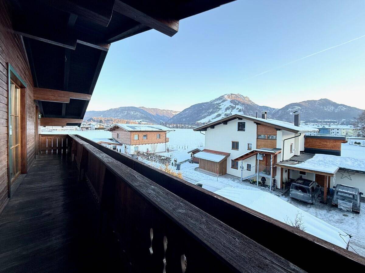 Langer Holzbalkon mit Bergblick und verschneiter Landschaft.
