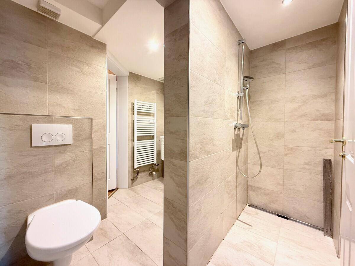 Modernes Badezimmer mit begehbarer Dusche, Wand-WC und beheiztem Handtuchhalter.