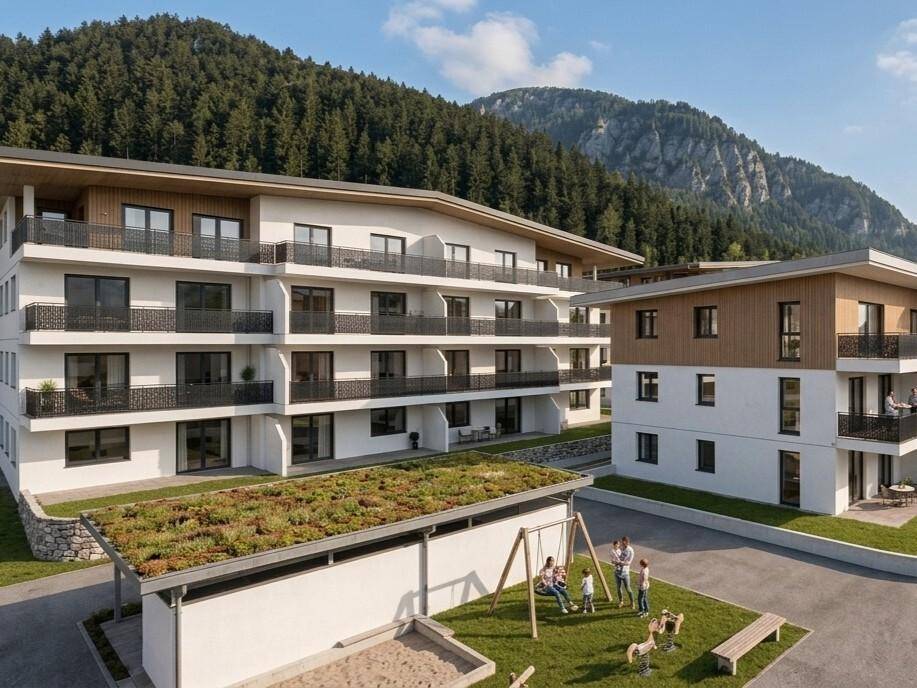 Moderne Wohnanlage mit mehreren Gebäuden, umgeben von Bergen und mit Kinderspielplatz.