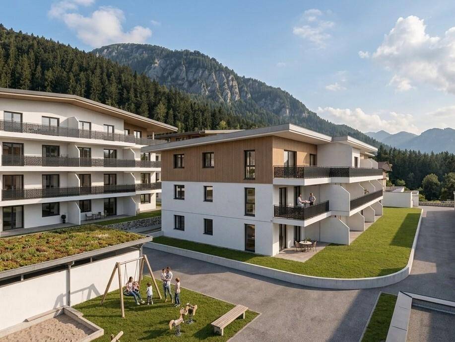 Neue Wohngebäude in alpiner Umgebung mit Spielplatz und Blick auf die umliegenden Berge.