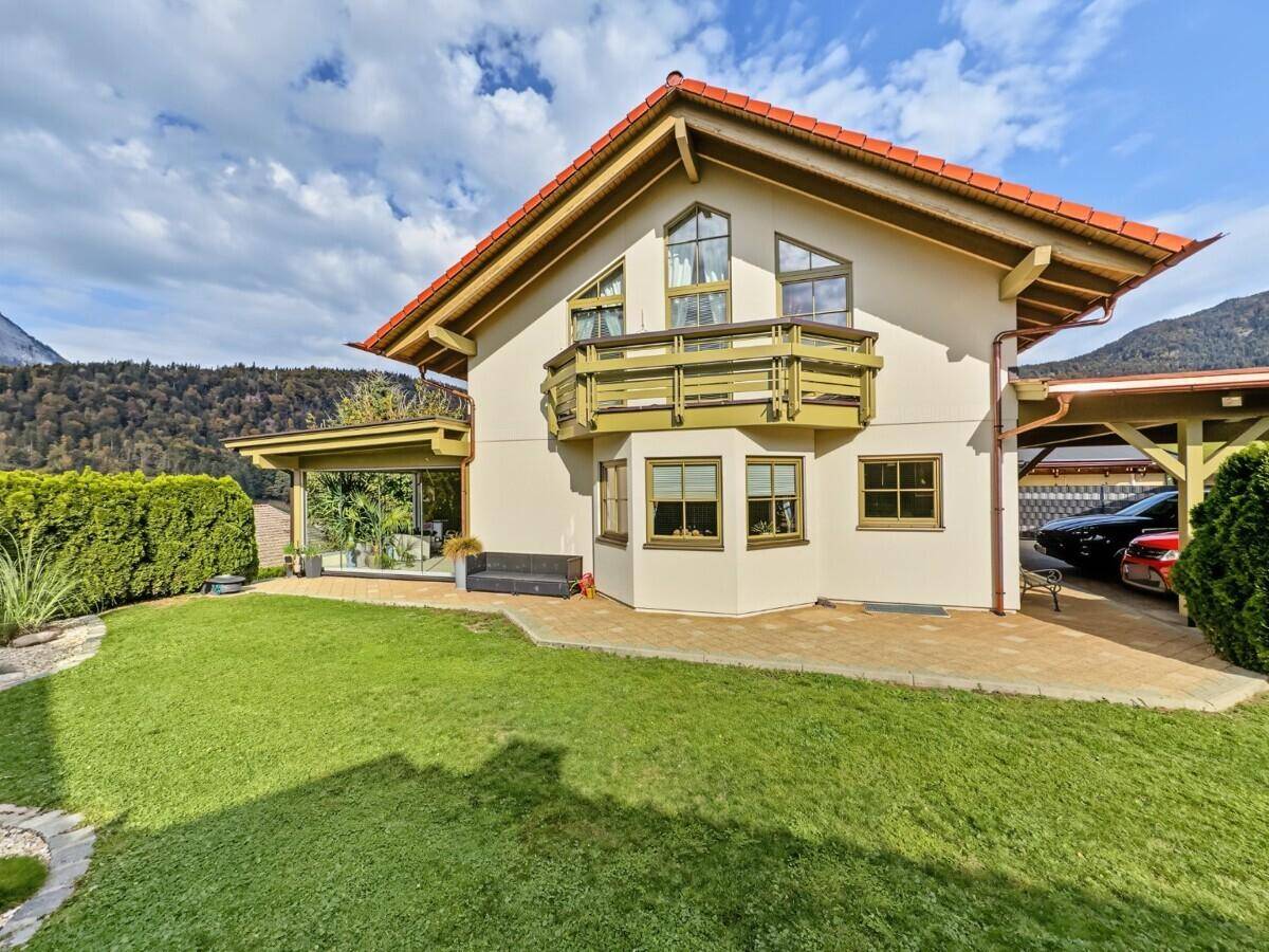 Freistehendes Einfamilienhaus mit gepflegtem Garten, Balkon und Carport in ländlicher Umgebung.