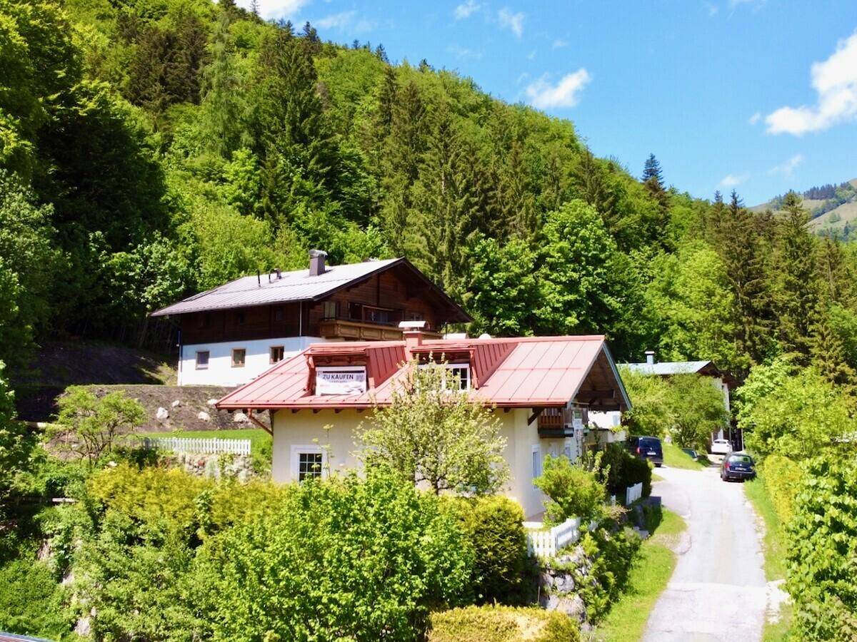 Haus in idyllischer Berglandschaft mit viel Grün und weiteren Gebäuden.