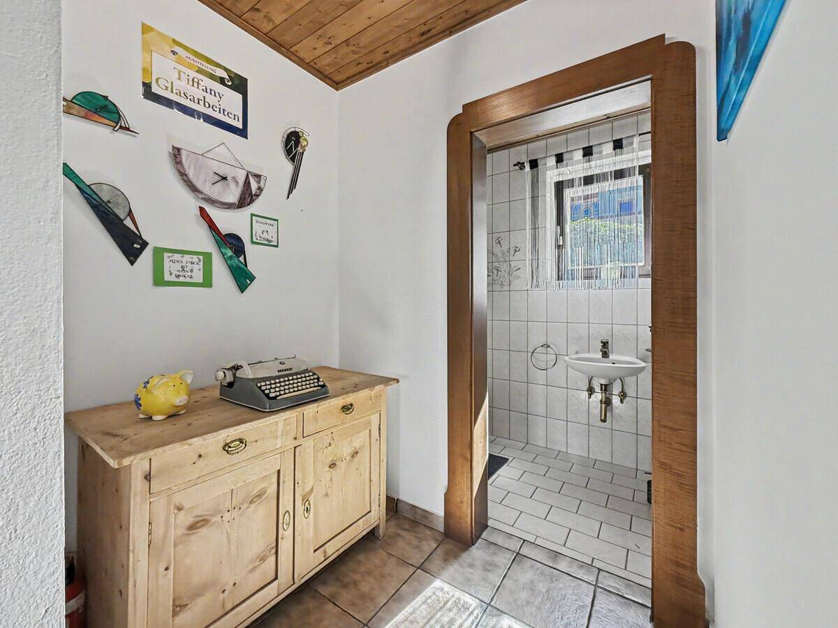 Kleines Badezimmer oder Gäste-WC mit weißen Fliesen, Waschbecken und Fenster.