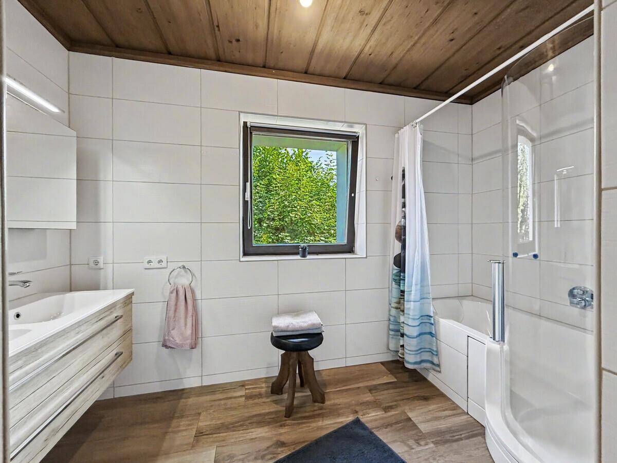 Helles Badezimmer mit weißen Fliesen, modernem Waschtisch und Dusch-Badewannen-Kombination.