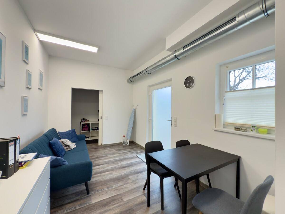 Pausenraum mit Sofa, Esstisch und Stühlen, ideal für entspannte Momente.