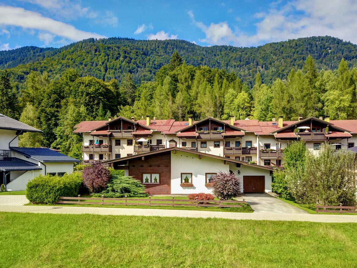 Traditionelles Gebäude im alpenländischen Stil mit Bergblick und gepflegter Gartenanlage.