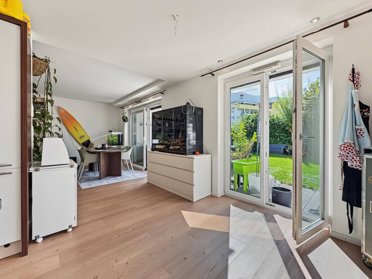 Heller Wohnbereich mit Holzboden, großen Fenstern und Blick auf den grünen Garten.