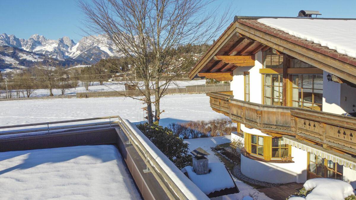 Weitläufige Winterlandschaft mit schneebedeckten Feldern und einer imposanten Bergkulisse.