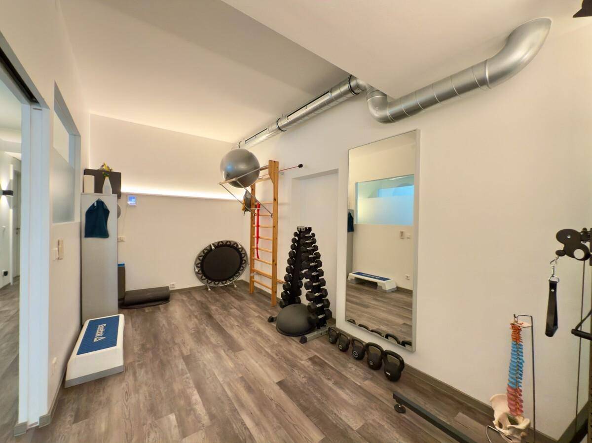Trainingsraum mit Sprossenwand, Hanteln und Trampolin, ideal für Physiotherapieübungen.