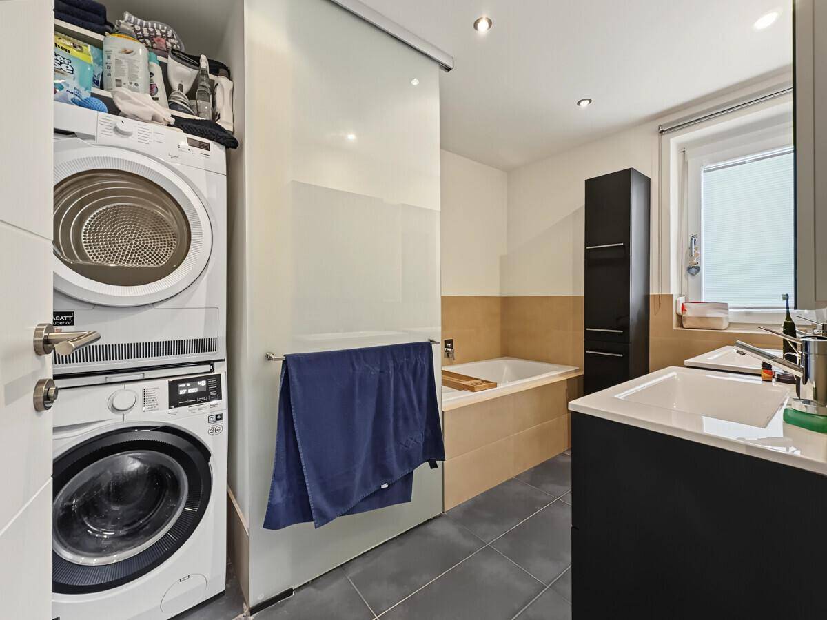 Badezimmer mit Waschmaschine und Trockner, Badewanne und Doppelwaschbecken.