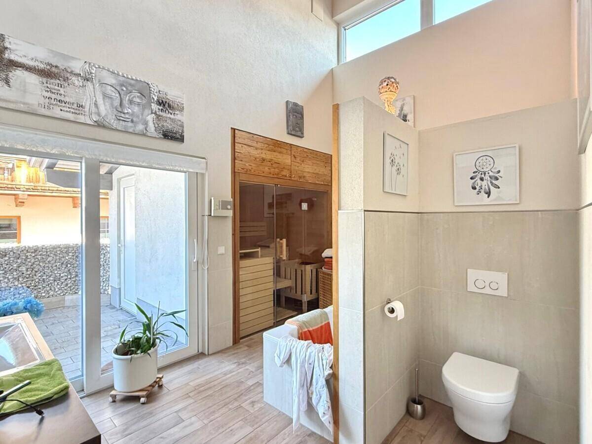 Modernes Badezimmer mit Sauna, WC und Zugang zu einer kleinen Außenterrasse.
