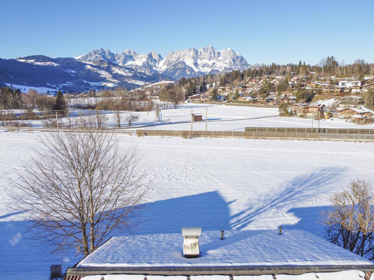 Weitläufige Winterlandschaft mit schneebedeckten Feldern und einer imposanten Bergkulisse.