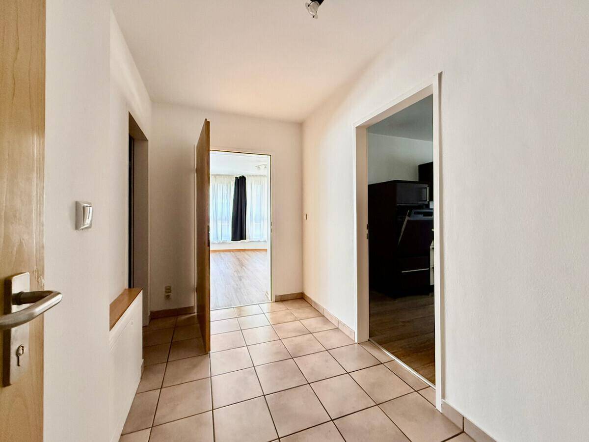Heller Flur mit Fliesenboden und offenen Türen zu anderen Räumen der Wohnung.