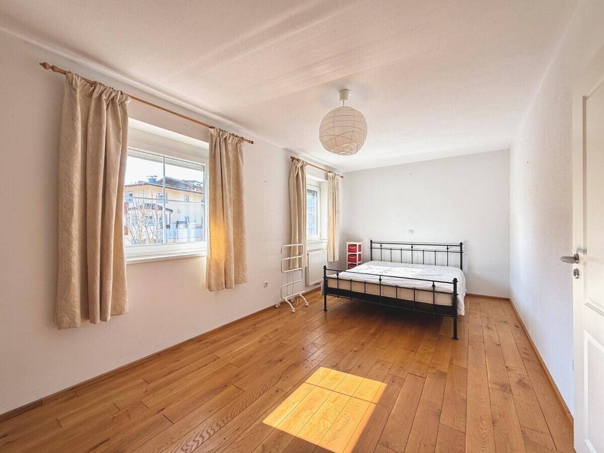 Helles Schlafzimmer mit weiß gestrichenen Wänden, Holzboden und viel natürlichem Licht.