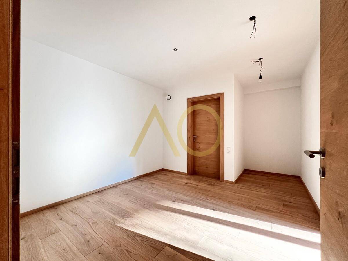 Helles Schlafzimmer mit Holzboden und schlichter Holztür, bereit zur Einrichtung.