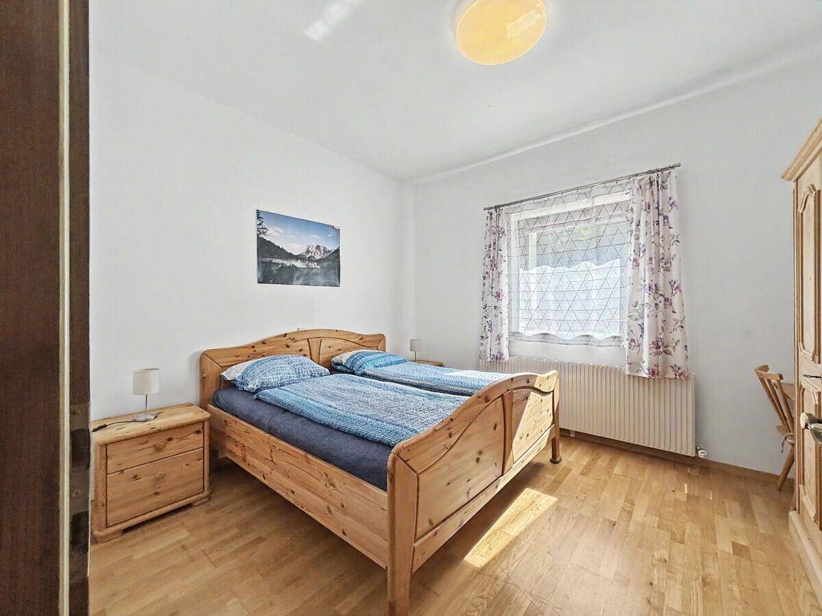 Gemütliches Schlafzimmer mit hellem Holzbett, Nachttischen und Kleiderschrank.