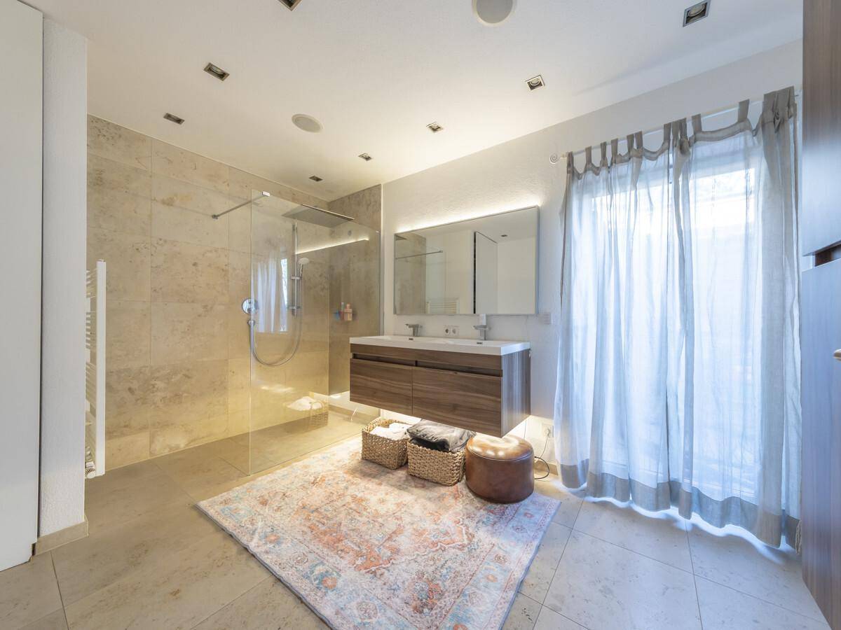 Modernes Badezimmer mit großer begehbarer Dusche, Doppelwaschbecken und Fenster.