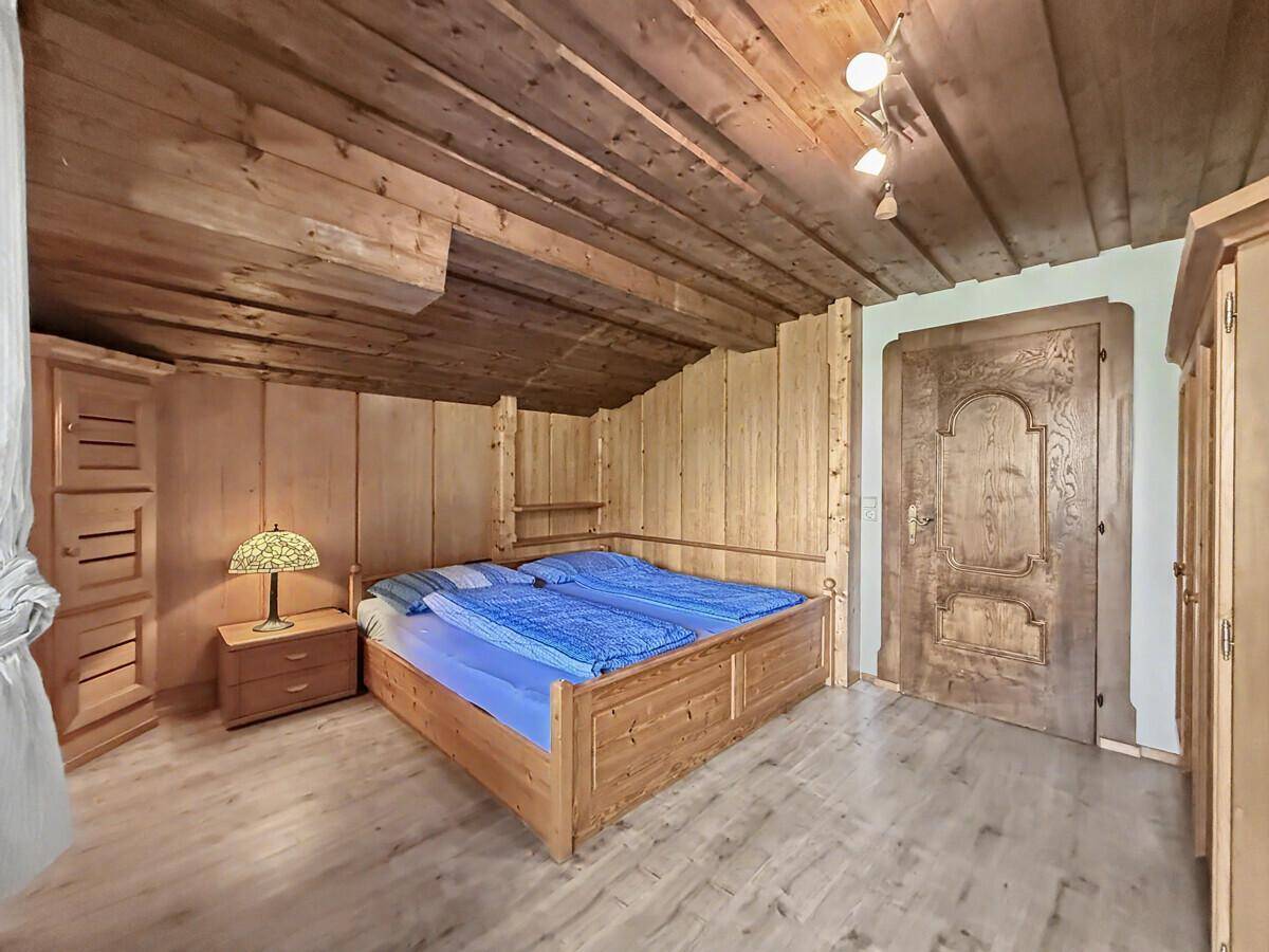 Gemütliches Schlafzimmer mit Holzbett, Nachttisch und Kleiderschrank, komplett in Holz gehalten.